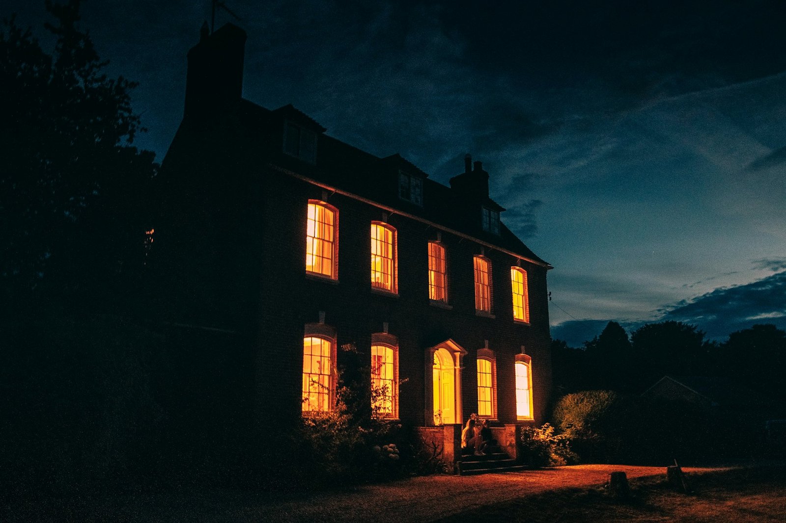 Maison en pierre aux fenêtres éclairées, à la tombée de la nuit